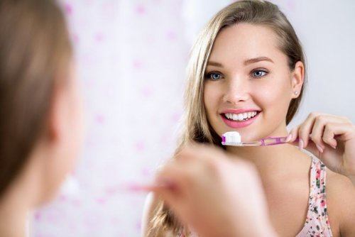 teen girl brushing her teeth in the mirror